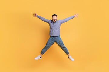 Fototapeta na wymiar Crazy Sales. Funny Asian Man Jumping Like A Star Over Yellow Background