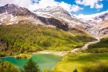 Naklejka na ściany i meble Green mountain valley with a lake and snow covered peaks in Swiss alps