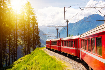 Naklejka premium Red train moving in beautiful green summer forest in Switzerland