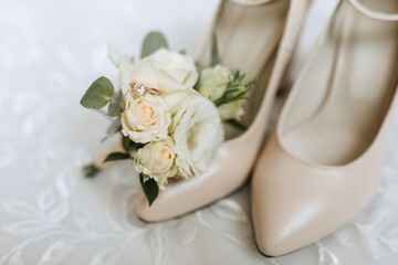 Elegant beige shoes. A small bouquet of flowers near women's shoes. Fashion. Style. Wedding photo. Details of the bride