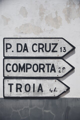 Road signs in Melides, Alentejo, directing the way to Pinheiro da Cruz, Comporta, and Troia.