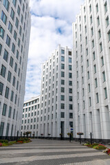 Side view of empty pedestrian street between tall white buildings. Blue sky with some clouds. Copy space for your text or decoration. Urban architecture theme.