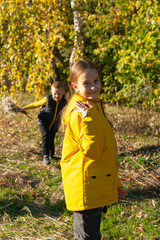 Brother and his cute sister are walking in the autumn forest. The boy has a bouquet of flowers in his hands. The girl looks at the camera