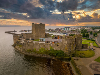 Fototapeta Aerial view of medieval Anglo Norman Carrickfergus castle with large rectangular keep dramatic sunset sky obraz