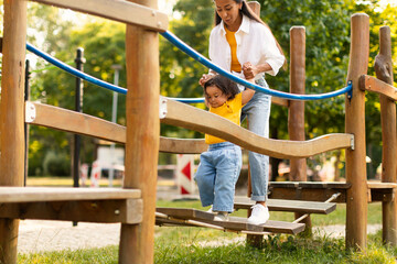 Obraz premium Korean Mom Engaging With Toddler in Playground Adventure in Park