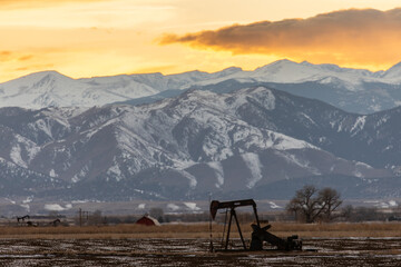Pump jack in field in front of mountains