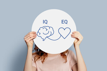 iq eq concept. girl holding poster with hand drawing a brain and heart - obrazy, fototapety, plakaty