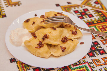 dumplings with sour cream on a plate,dumplings with fried onions embroidered tablecloth