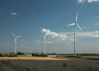 turbiny wiatrowe na polu uprawnym w słoneczny dzień. Krajobraz rolniczy. Koncepcja czystej...