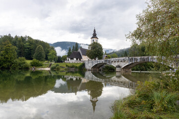 Fototapeta na wymiar Slowenien: Bohinj See mit Kirche und Brücke und Spiegelung