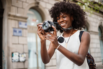 Young black female tourist enjoys walking through the streets of a beautiful European city. She is...