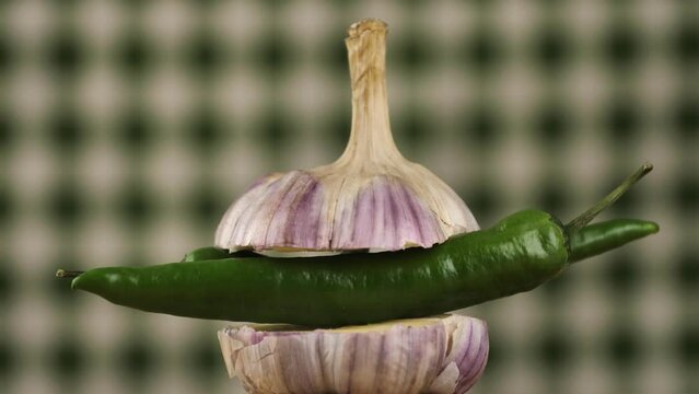 rotating young garlic with hot pepper inside on a checkered background.Young garlic and peppers are hot and tender.
