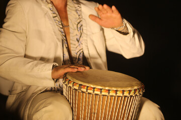 Ritmo e Tradição: Mãos masculinas habilidosas acariciam o tambor, entre as pernas, vestindo uma...