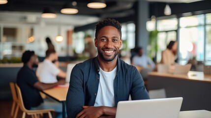 Black african american man working on a laptop in the office and smiling