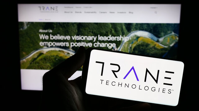 Stuttgart, Germany - 08-11-2023: Person holding smartphone with logo of Irish company Trane Technologies plc on screen in front of website. Focus on phone display.