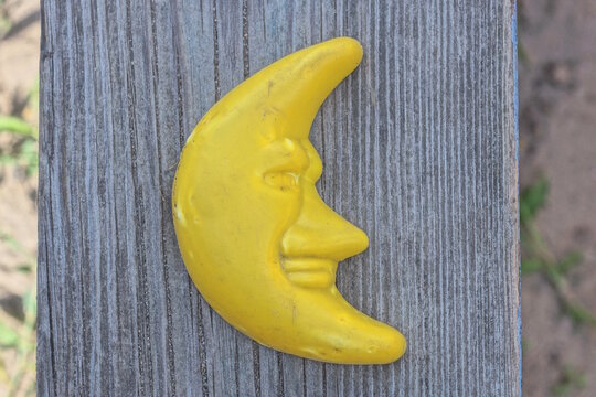 one plastic yellow small dirty toy moon lies on a gray wooden table board in the street