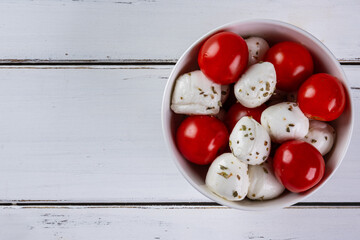 buffalo mozzarella balls and cherry tomatoes in white bowl