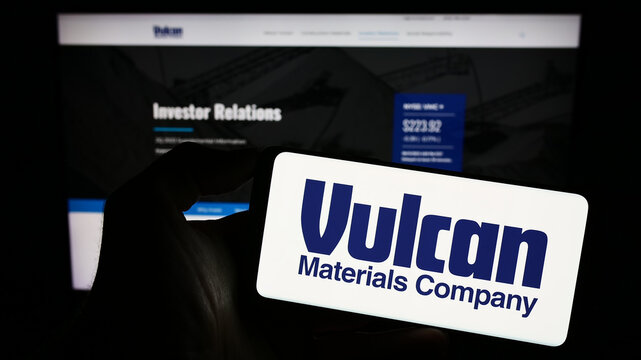 Stuttgart, Germany - 08-12-2023: Person holding cellphone with logo of US business Vulcan Materials Company on screen in front of business webpage. Focus on phone display.