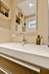 a modern bathroom with beige tile walls and white counters, along with a large mirror above the sink area