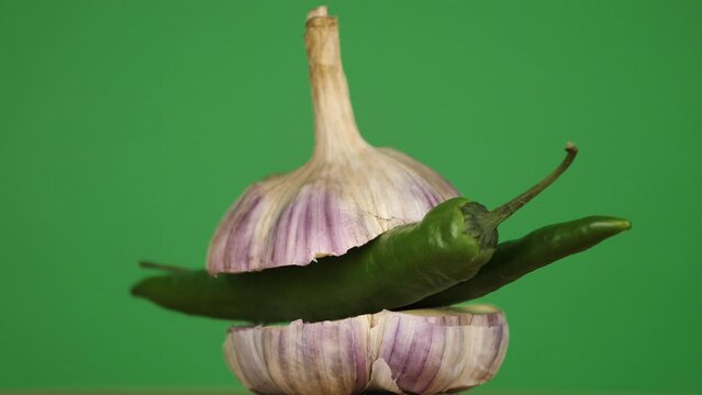 rotating young garlic with hot pepper inside on a green background
