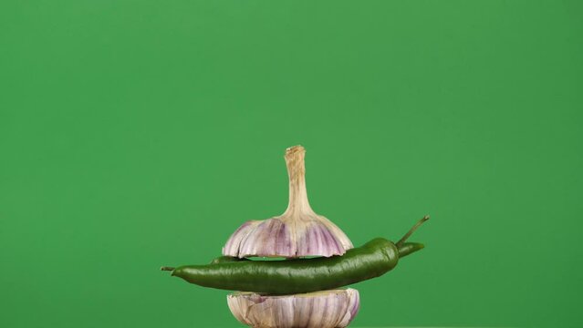 rotating young garlic with hot pepper inside on a green background