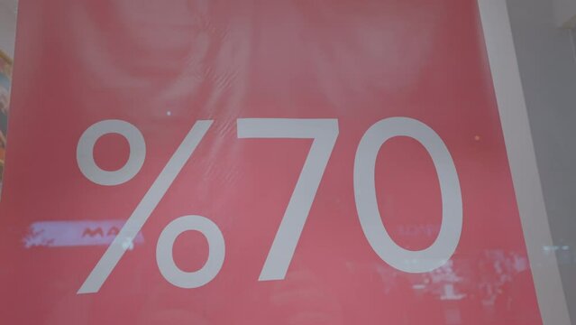 Big red promotion banner with 70 percentage discount text fixed behind window case glass of clothing shop