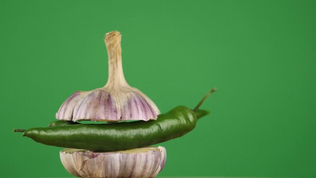 rotating young garlic with hot pepper inside on a green background.Copy space. place for text.