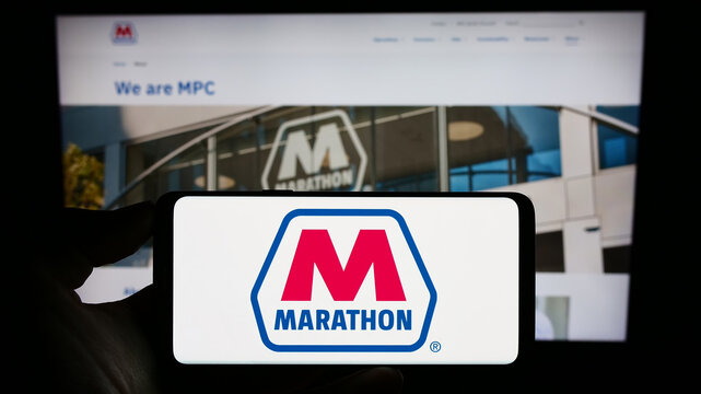 Stuttgart, Germany - 08-13-2023: Person holding cellphone with logo of American oil company Marathon Petroleum Corporation on screen in front of webpage. Focus on phone display.