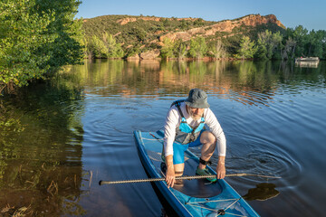 senior male is paddling a stand up paddleboard, Horsetooth Reservoir near Fort Collins, Colorado,...
