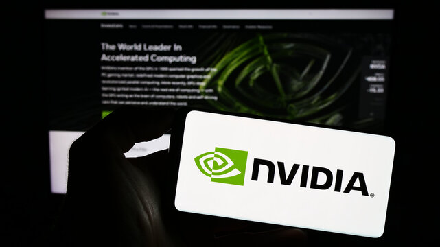 Stuttgart, Germany - 08-13-2023: Person holding mobile phone with logo of American technology company Nvidia Corporation on screen in front of web page. Focus on phone display.