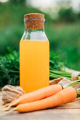 Fresh carrots on a wooden background. Food for vegetarians. Homemade vegetables, eco-friendly, healthy food. Glass jug with carrot juice on a wooden table.