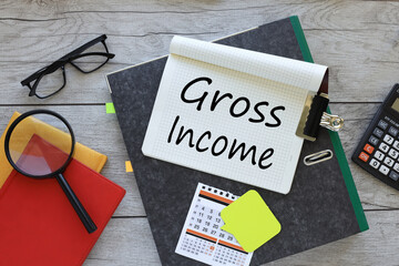 GROSS INCOME text on a notebook on a folder. red notepad. magnifying glass