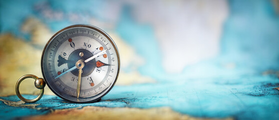 Magnetic old compass on world map.Travel, geography, navigation, tourism and exploration concept wide background. Macro photo. Very shallow focus.