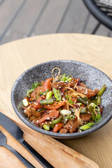 A bowl of udon noodles, veal and fried vegetables angle view on wooden table