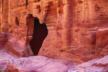 View of the wall with the door, the entrance to the temple, carved into the red sandstone rock in the canyon. Petra, Jordan