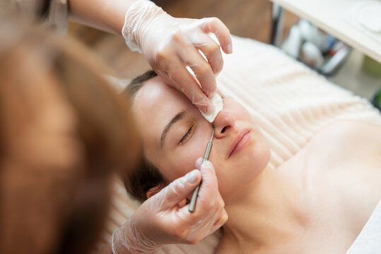 Skin care and cleaning in cosmetology clinic. Doctor cleaning pores on the client nose and face, using special cosmetology tools