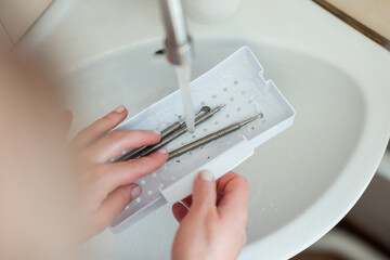 Close up on tools for mechanical cleaning of skin while washing and disinfecting them. Washing cosmetological tools for skin cleaning under the tap after using them