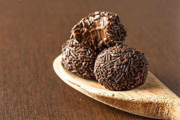two brazilian brigadeiro (brigadier) with chocolate sprinkles on a wooden spoon over wooden table. traditional brazilian candy for party dessert