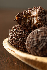 two brazilian brigadeiro (brigadier) with chocolate sprinkles on a wooden spoon over wooden table. traditional brazilian candy for party dessert