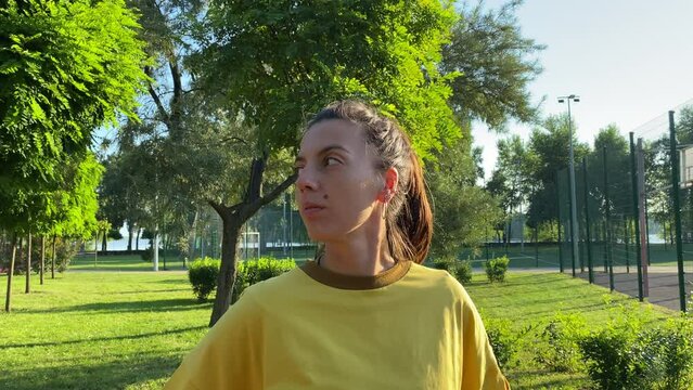 Serene multiracial young woman performs morning training in landscaped public park. She performs neck stretching head tilt exercise in golden sunlight clear sky. Active lifestyle, vitality flexibility
