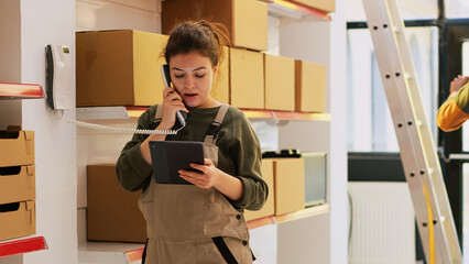 Manager talking to someone in storehouse, answering landline phone call to discuss with dispatcher...