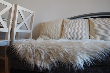 Gray sofa with boucle upholstery fabric and white decorative fluted cushions. White rug or...
