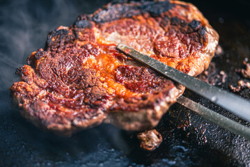 Close up of beef steaks cooking on grill in backyard barbecue.