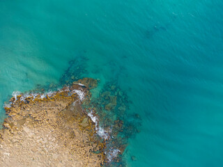 view from above of a rocky sea ledge, in a sea of crystal clear turquoise waters, cape rocky, coastline, drone view