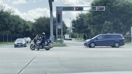 A police officer is directing traffic to allow for a funeral procession to move through an intersection.