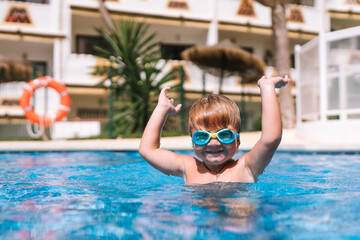 little boy swims in the pool in swimming goggles