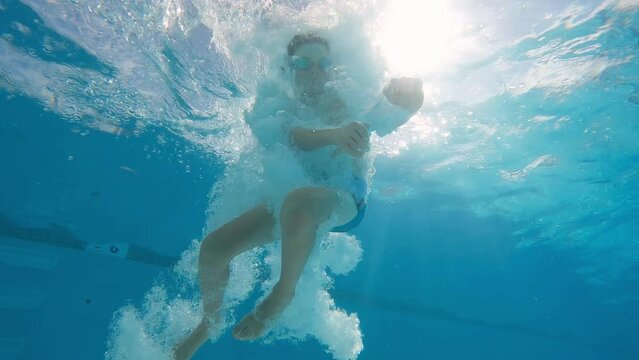 Underwater slow motion 10 year old boy plunges into the water on summer day