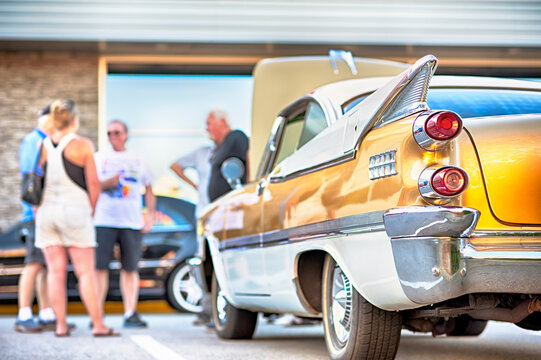 People gather to view classic muscle cars at vintage automotive exhibition. 