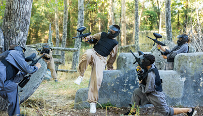Tactical paintball players training on battlefield, charging opponent covers, jumping over...