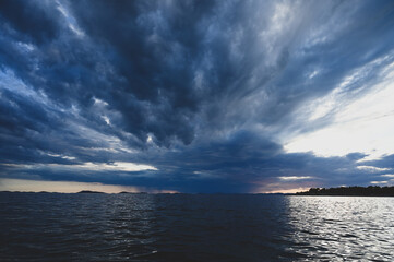 Dramatic dark clouds over the sea. Rain clouds at sunset.